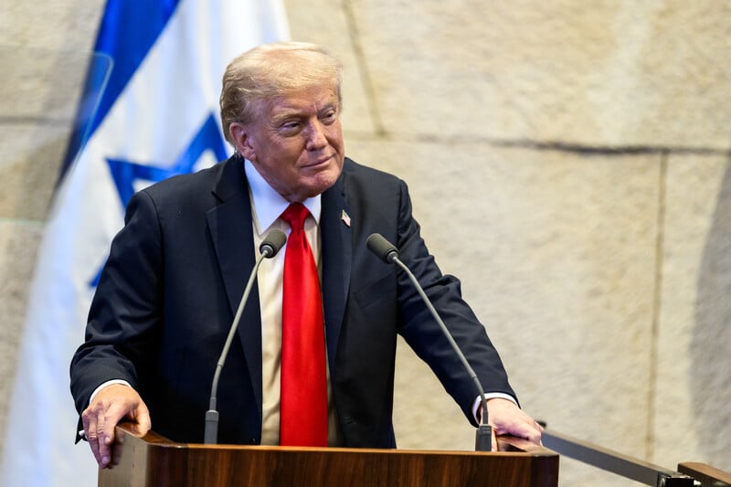 Trump speaks in front of an Israeli flag