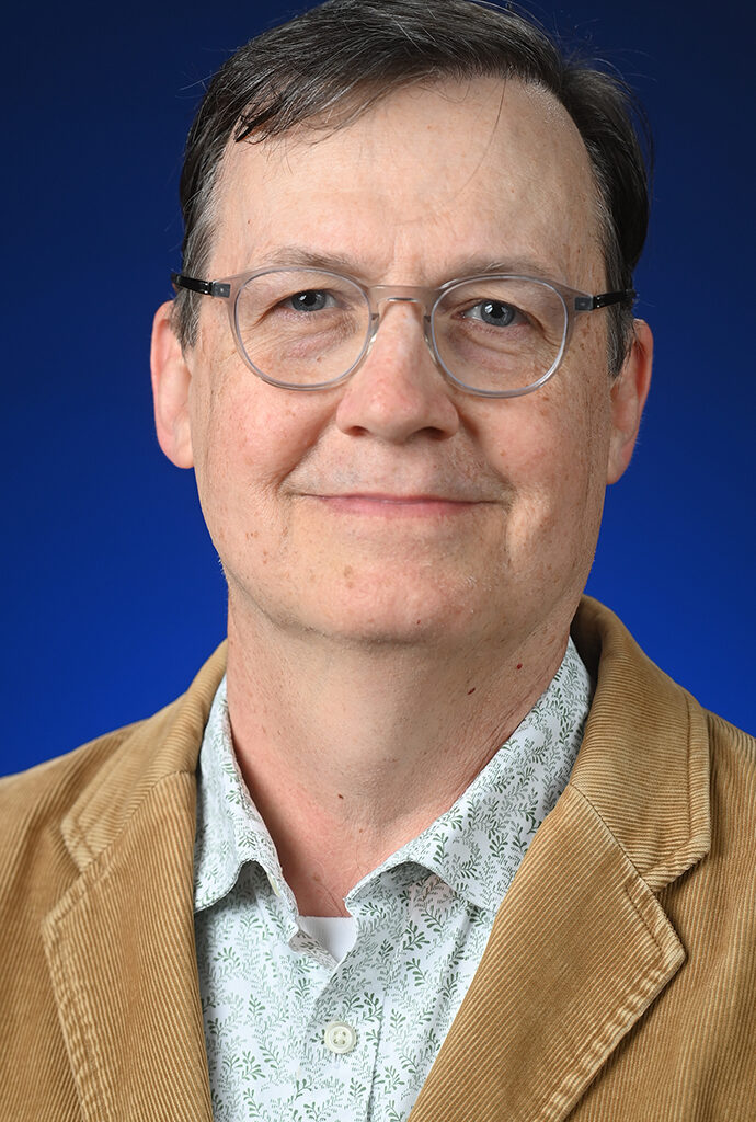 Headshot of a man wearing a tan jacket.