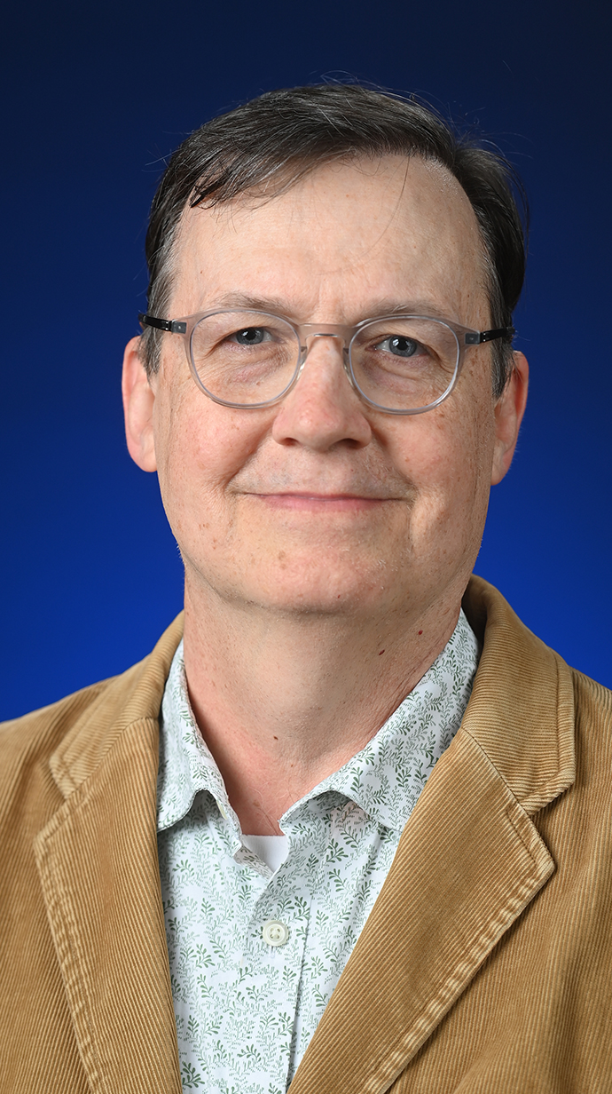 Headshot of a man wearing a tan jacket.