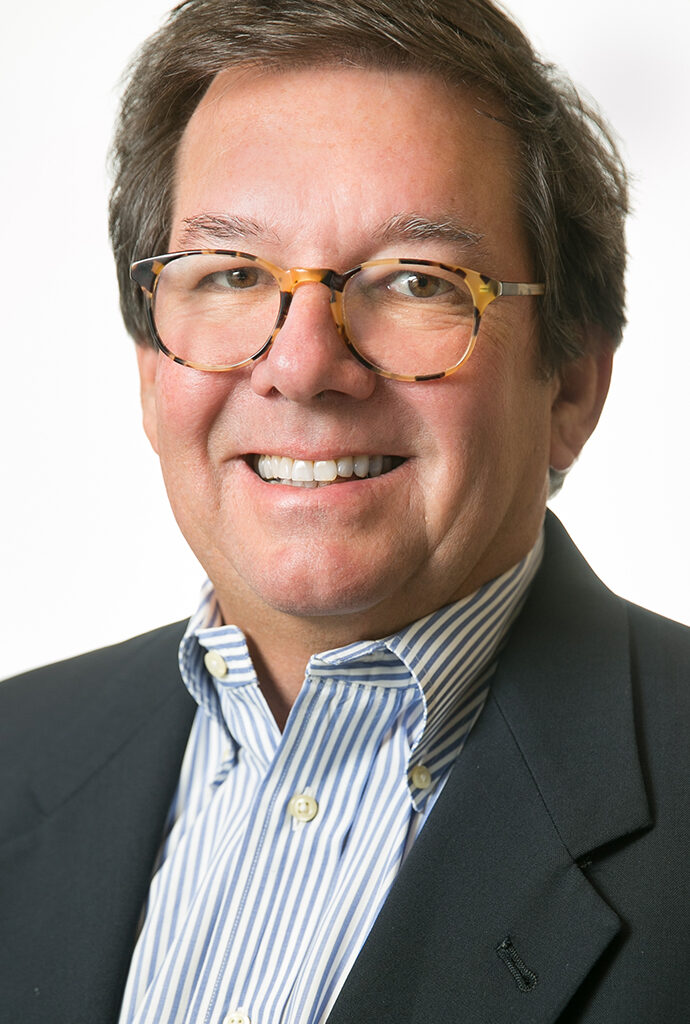 Headshot of a man wearing a gray sport coat and a blue striped shirt.