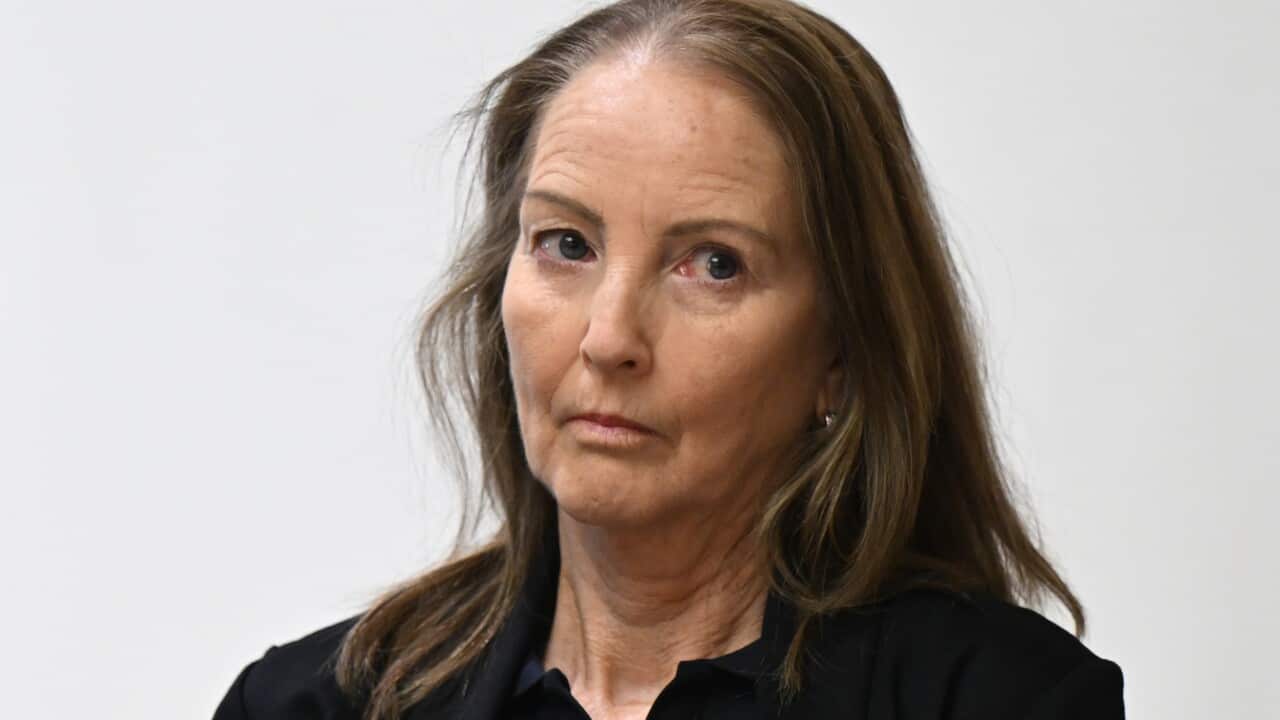 A woman with long brown hair wearing dark clothing