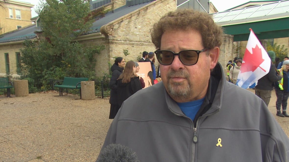 A man with brown curly hair and glasses.