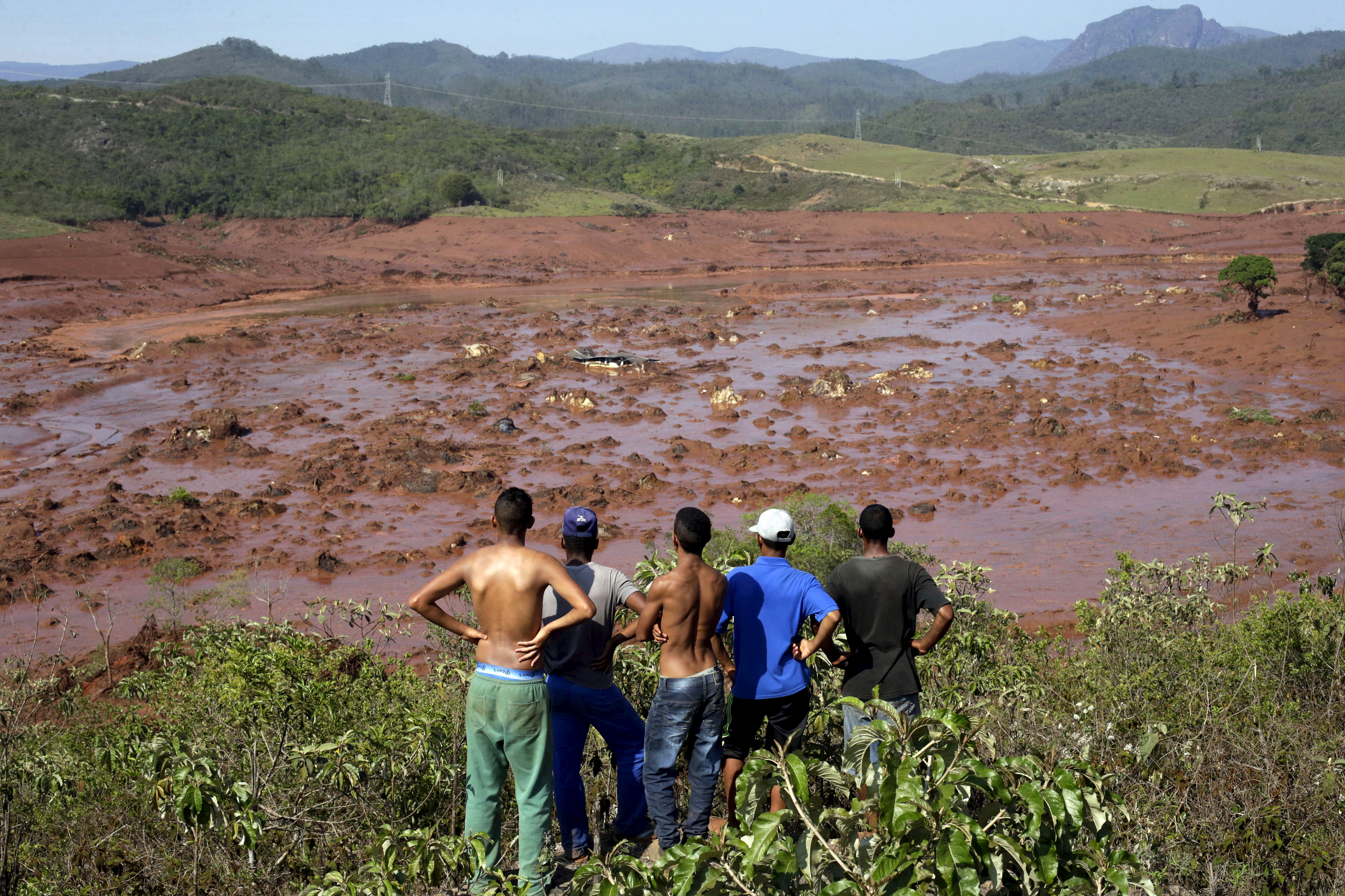 Five men observe the Bento Rodrigues district covered with mud after a dam burst in Mariana, Brazil.