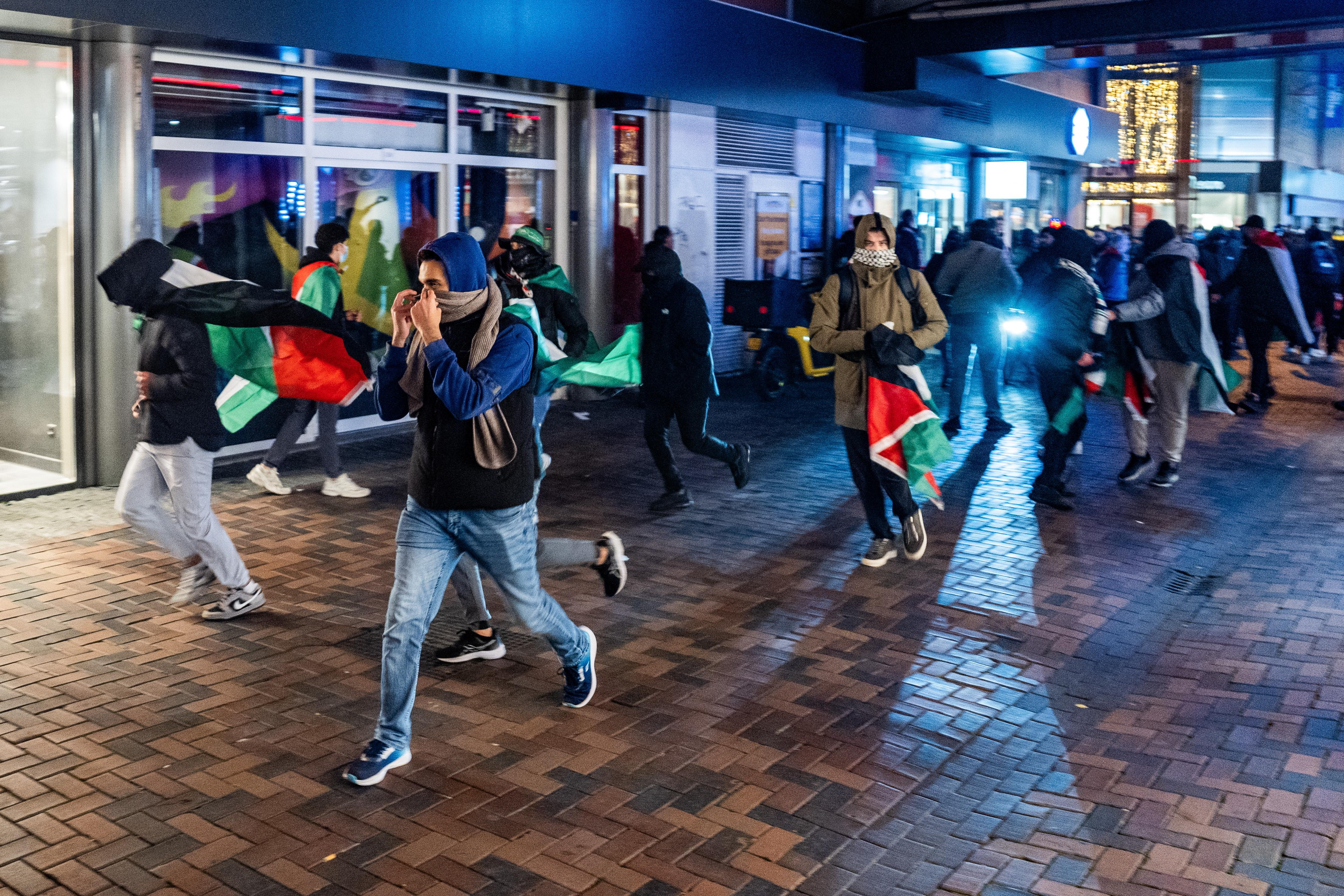 Demonstrators running with Palestinian flags.