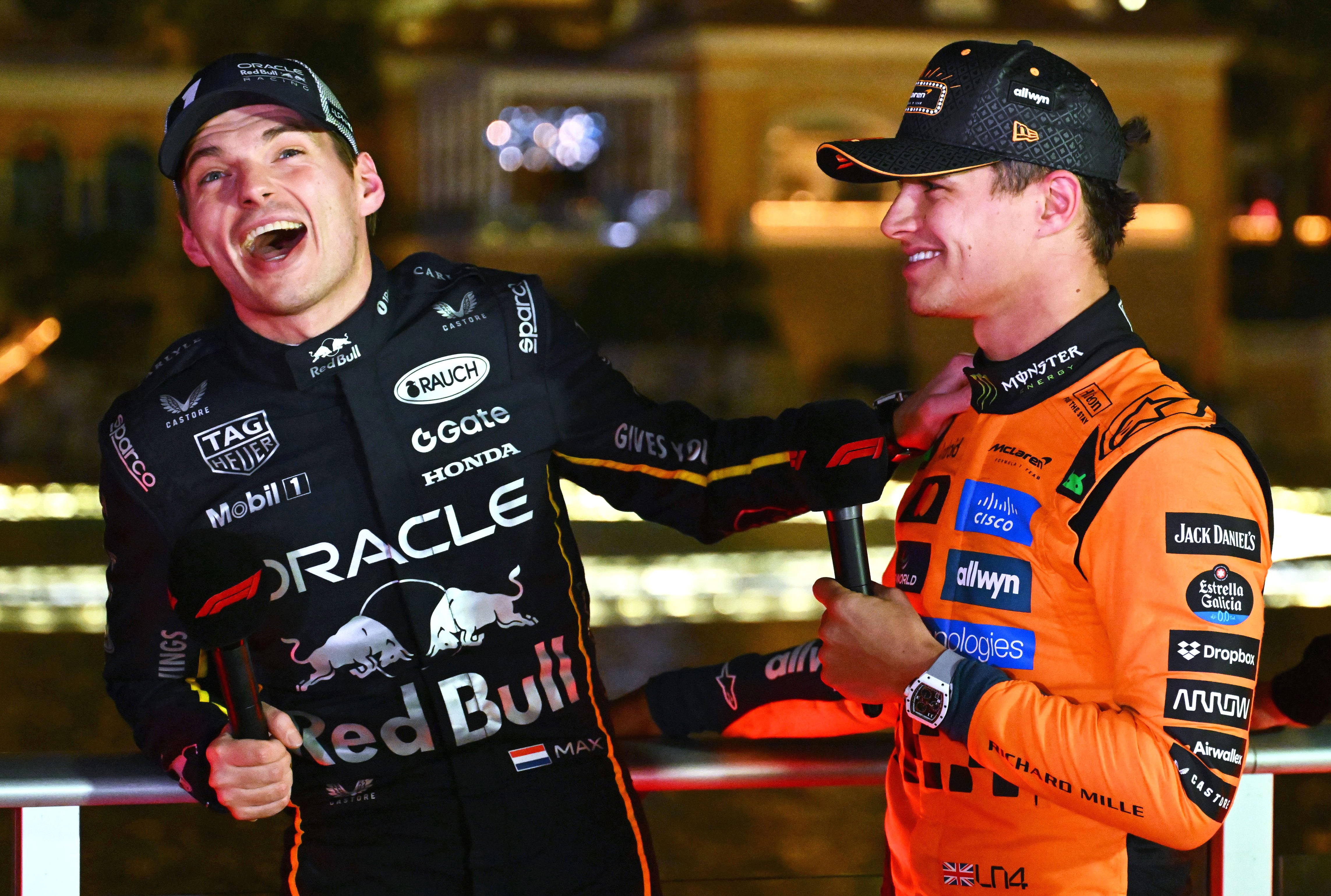 Three Formula 1 drivers, Max Verstappen, Lando Norris, and George Russell, laugh together during an interview.