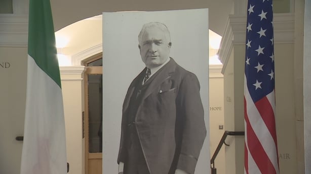 William Bourke Cockran's image on a board flanked by an Irish flag on the left and a US flag on the right.