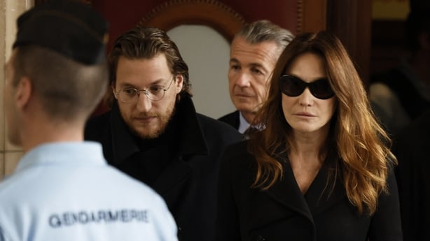 Carla Bruni and Jean Sarkozy pictured arriving at a Paris court with a police officer in the foreground