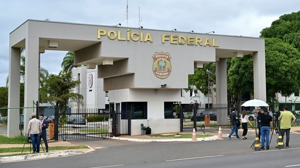 Journalists stand outside the Brazilian Federal Police Headquarters in Brasilia on November 22, 2025, where former President Jair Bolsonaro was transferred earlier.