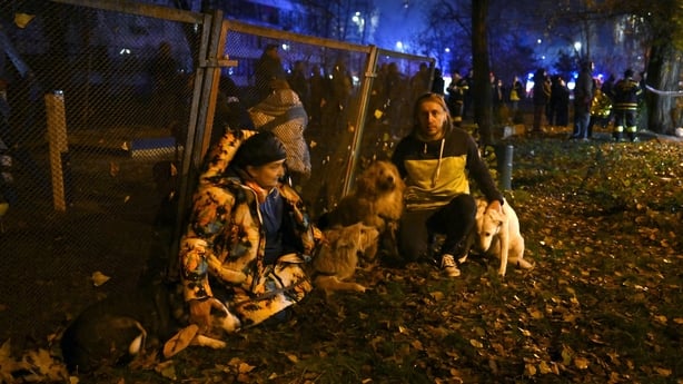 Residents stand outside after evacuating a damaged residential building following Russian missiles and drones strikes in Kyiv