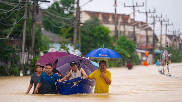 People wade through flood waters with residents being evacuated on a boat in Hat Yai in Thailand