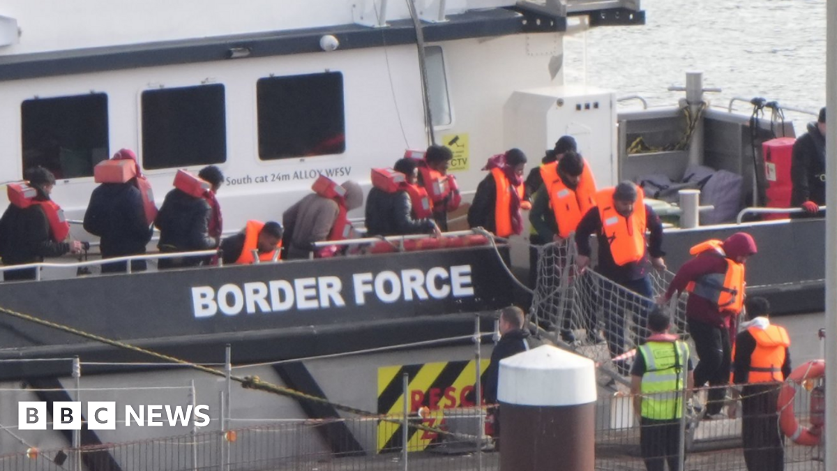 Migrants in hi viz jackets disembark from a Border Force boat