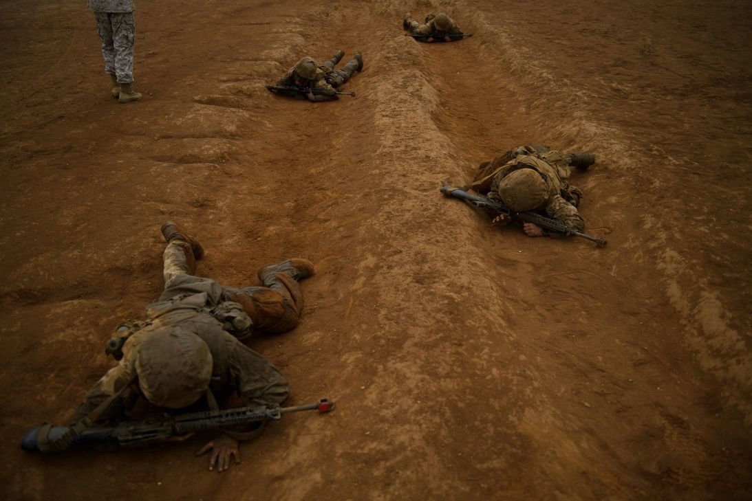 United States Marine Corps recruits from Lima Company crawl on their stomachs during an obstacle course during The Crucible, the final part of phase three of recruit training before officially becoming US Marines, at Camp Pendleton in 2021.