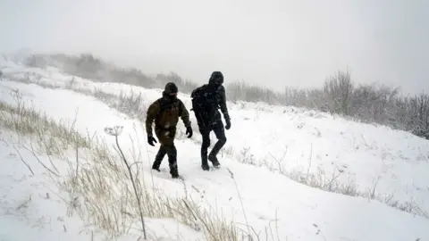 Danny Lawson/PA Wire People walking through the snow on the North York Moors.