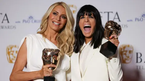 Reuters Both clad in white, Tess Daly and Claudia Winkleman, winners of the Entertainment category for Strictly Come Dancingpose with awards at the 2024 BAFTA Television Awards in London.