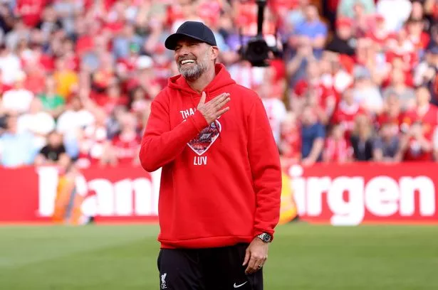 Jurgen Klopp smiles and looks on while on the pitch at Anfield