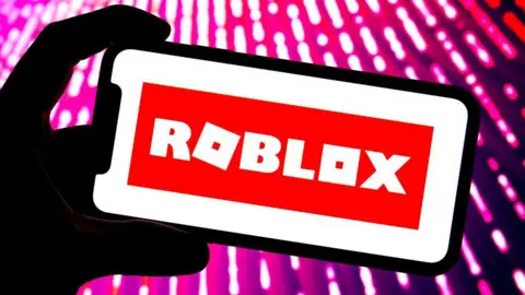 Getty Images  Silhouette of a mobile phone with the Roblox branding on the screen. 
