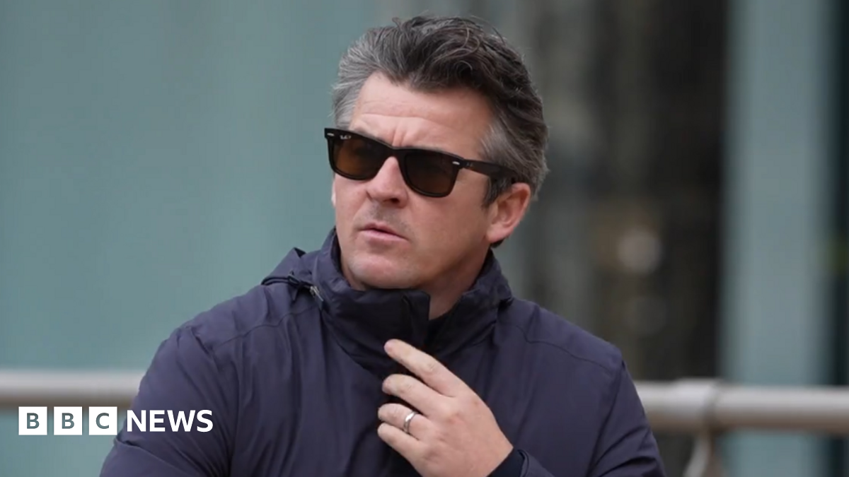 Joey Barton has dark greying hair and wears sunglasses. He is wearing a navy blue jacket