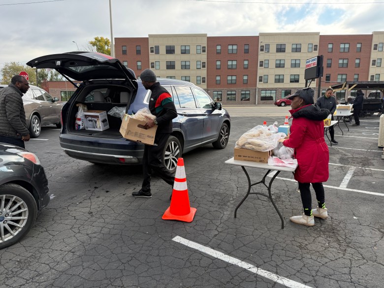 People in a parking lot. They are loading food in a car.