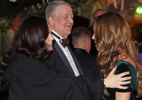 Reuters Jessie J with her hands on the Princess of Wales's shoulders as they are in conversation, with Stephen Fry in the background slightly smiling 
