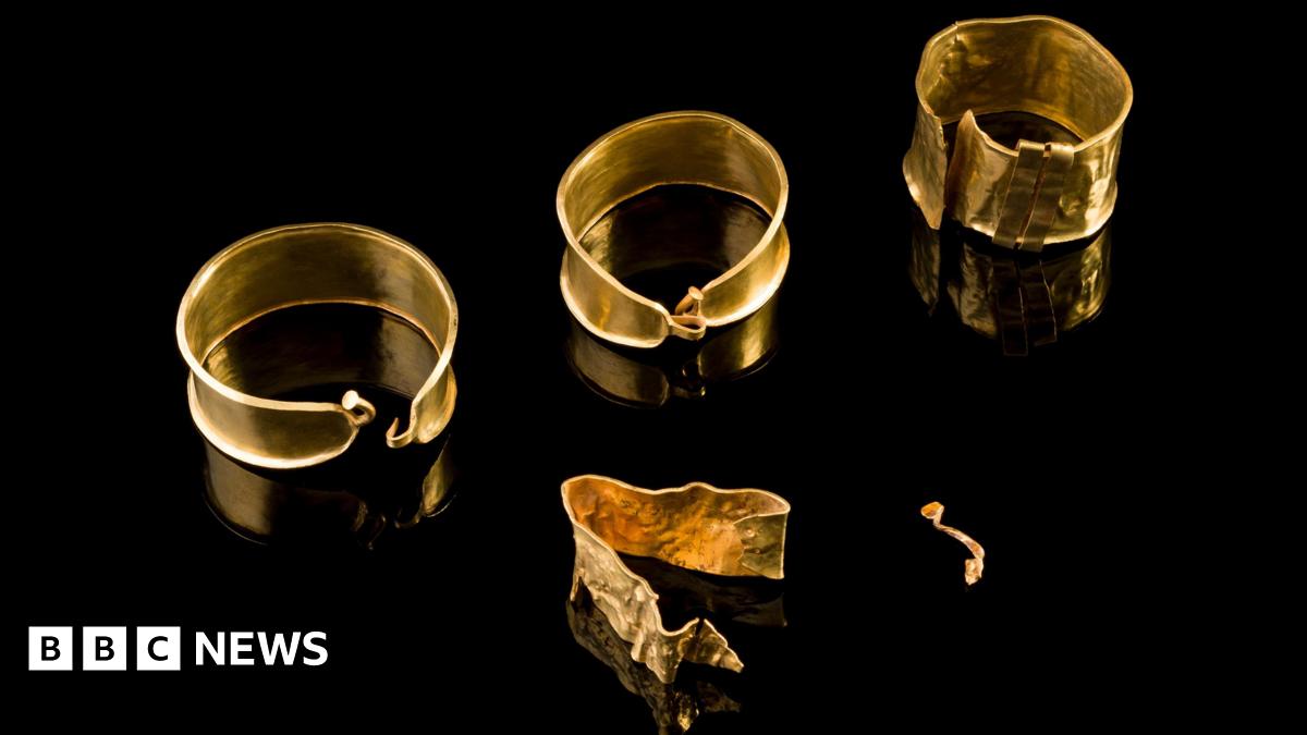 Gold jewellery dating back to the Bronze Age laid out on a black surface.