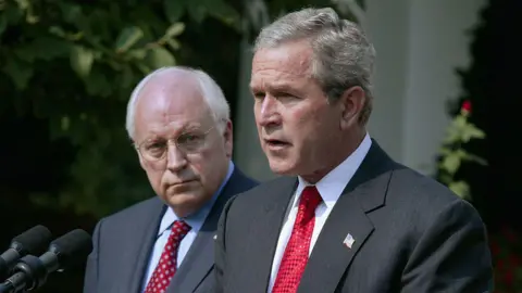 Brooks Kraft LLC/Corbis via Getty Images George W Bush speaks at a lectern at the White House in 2004, and Cheney, standing next to him, looks at him.