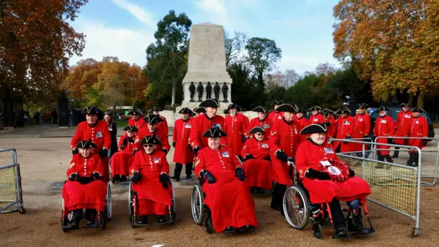 A group of veterans, all wearing red with black hats, arriving