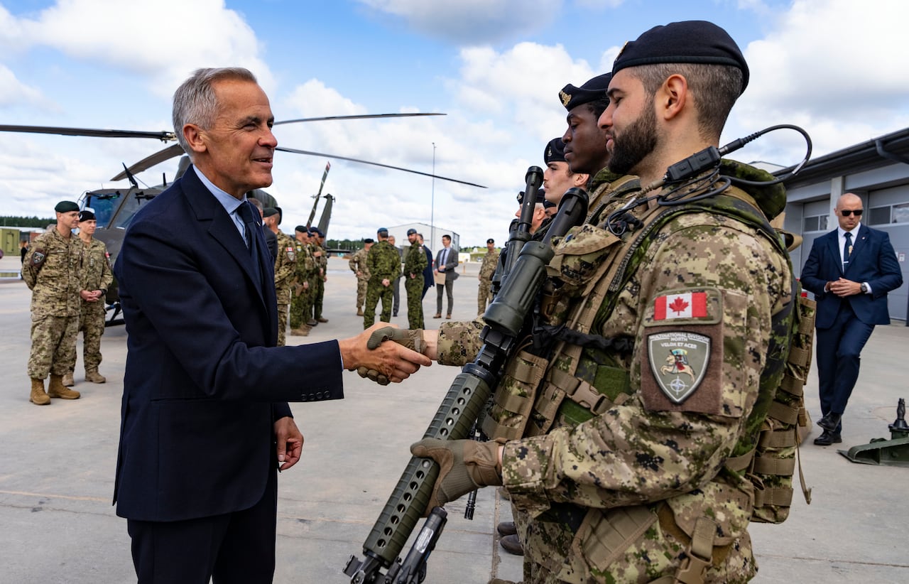 A  man in a suit shakes hands with a man in a military uniform.