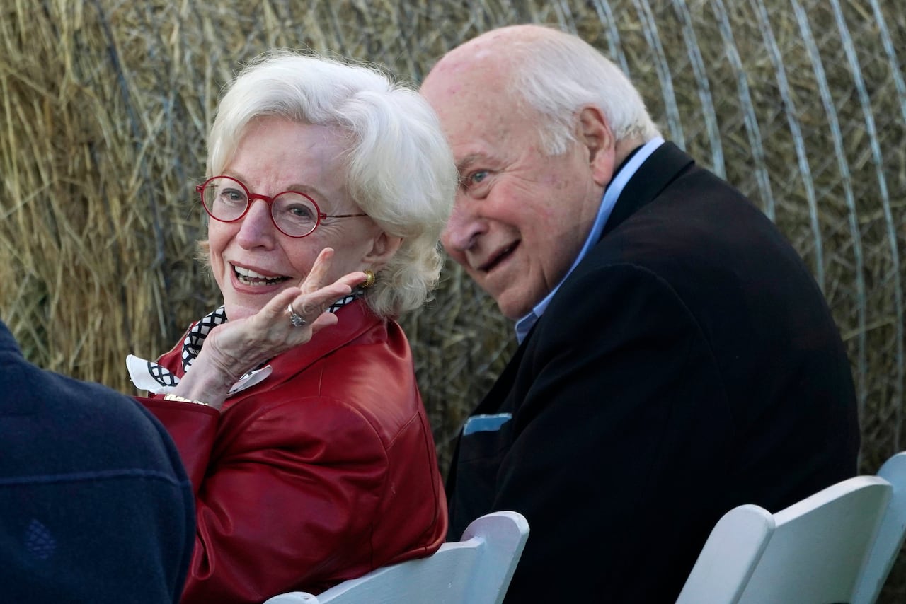 An older, Caucasian couple are shown seated and smiling.