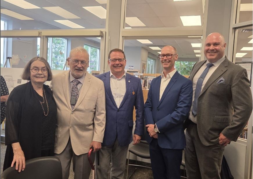 Five people stand side by side smiling.