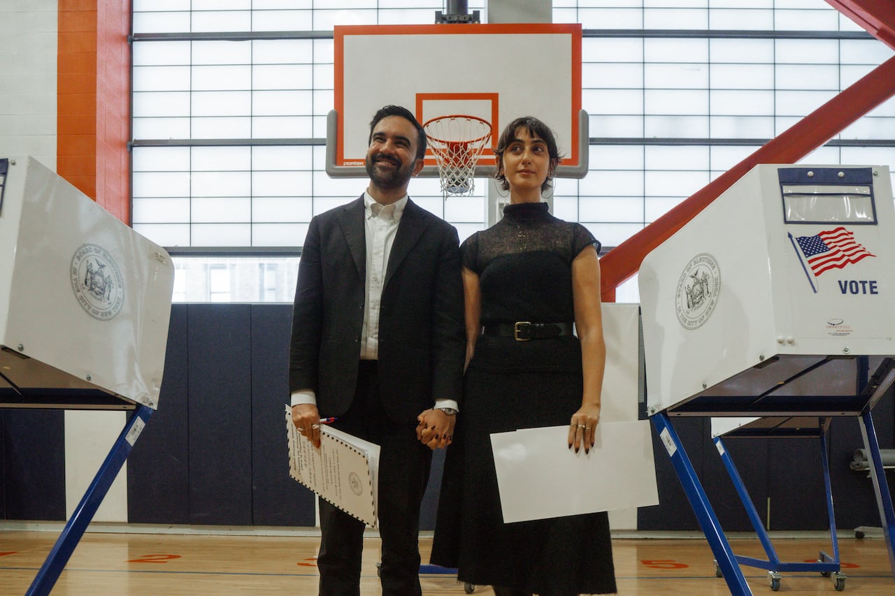 a man and woman stand side by side near a polling station