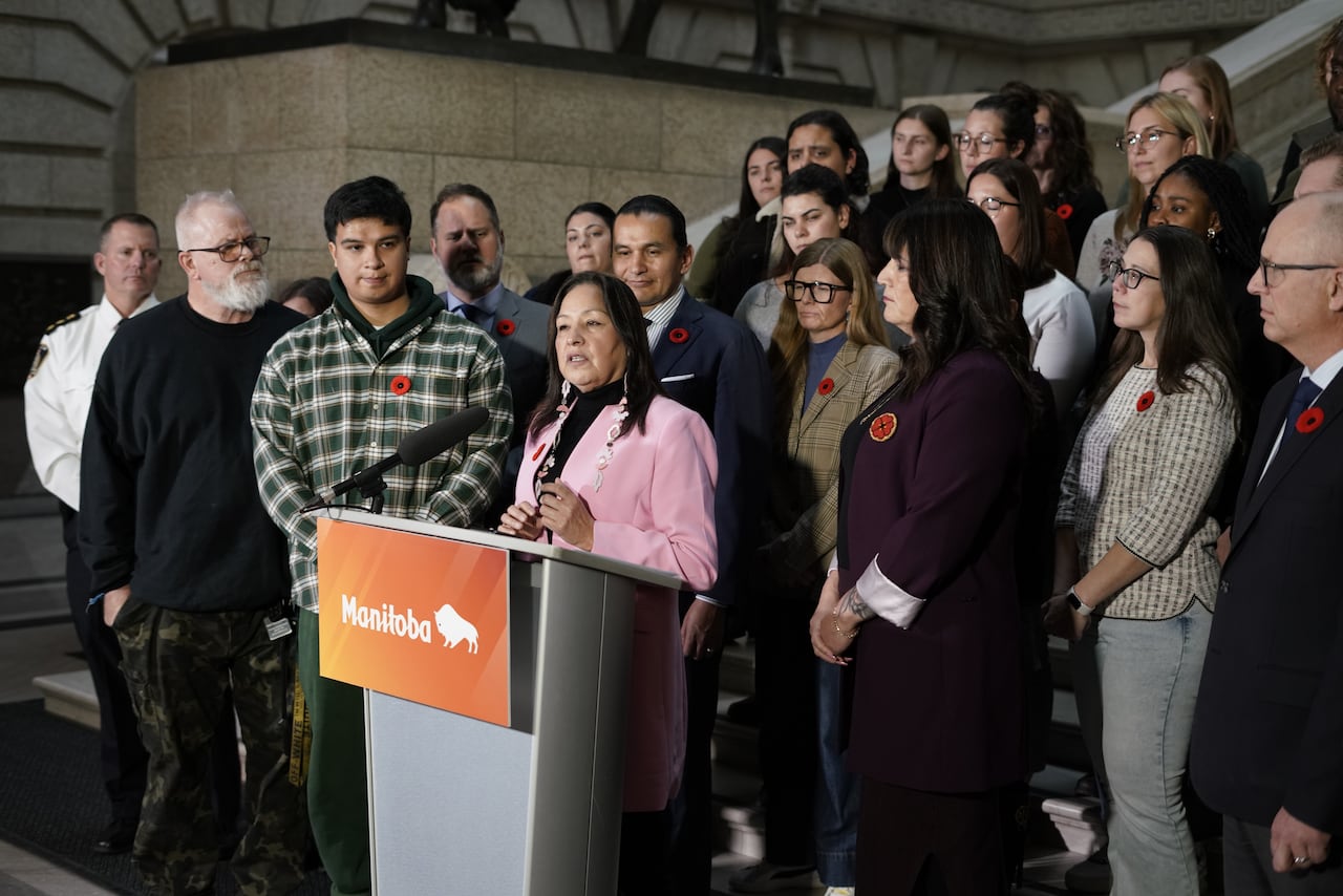 A group of people speak from behind a lectern at the bottom of a long staircase.