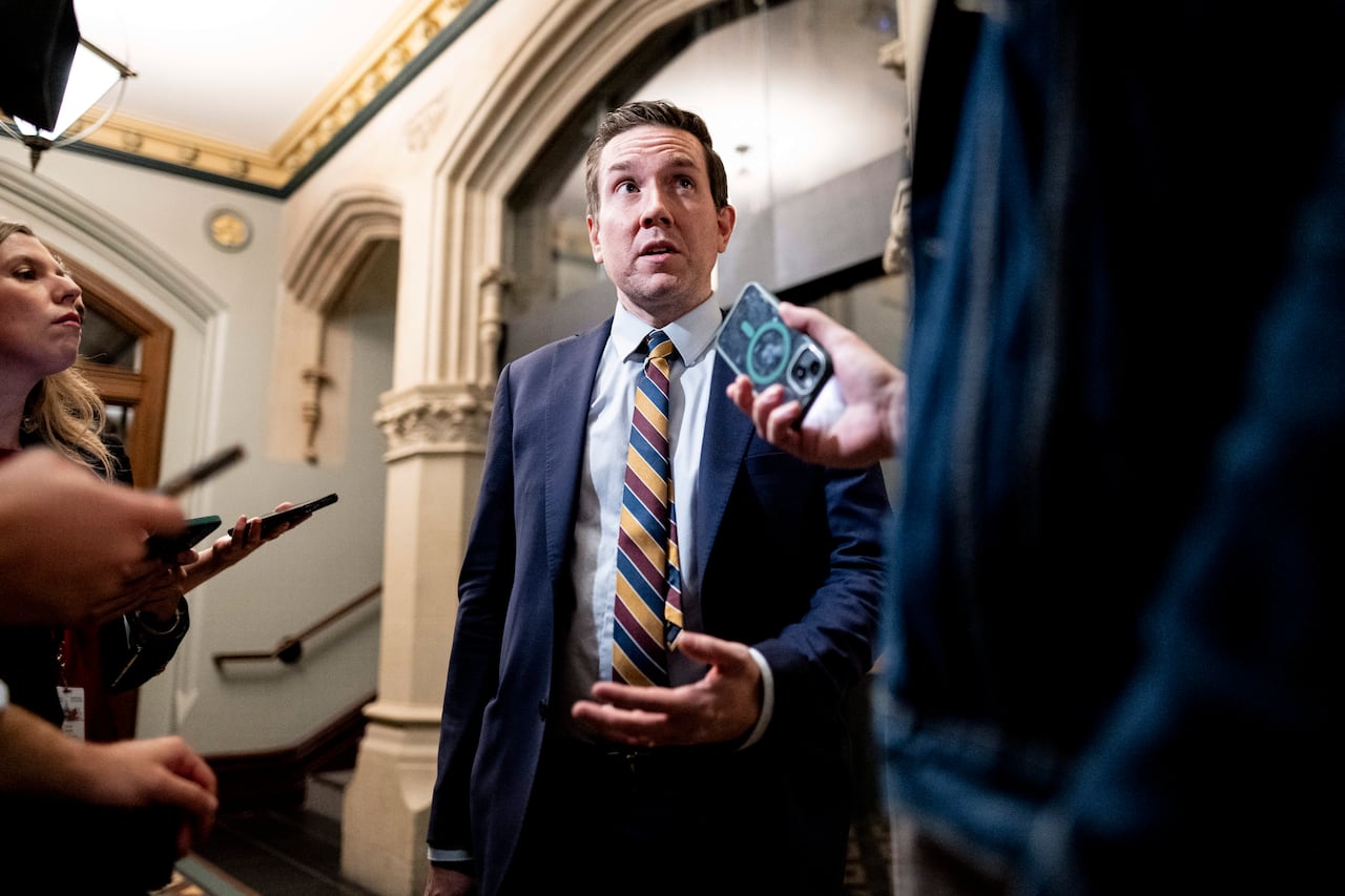 A man speaks in front of reporters.