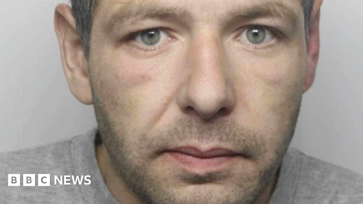 Mugshot of a man with a short beard, wearing a grey jumper.