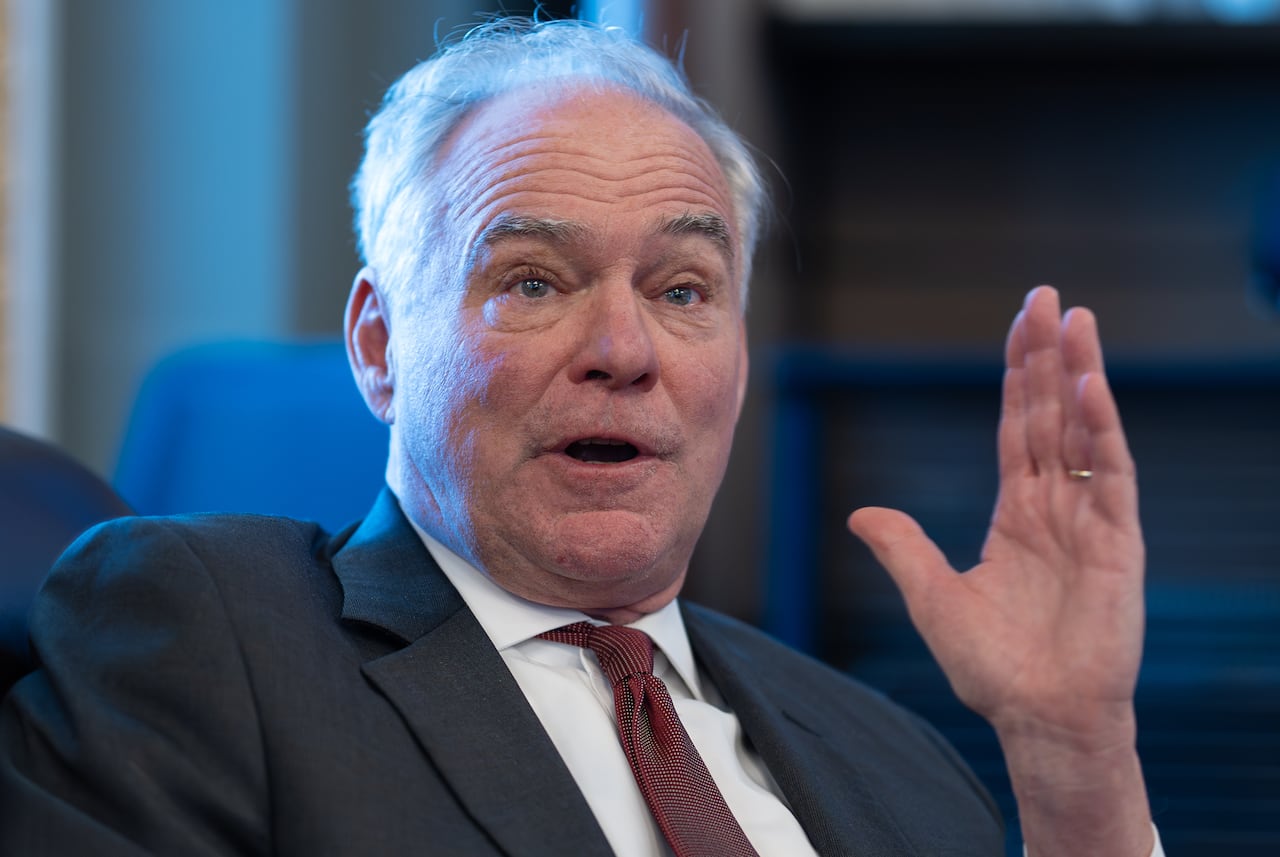 A man wearing a suit speaks to reporters. 