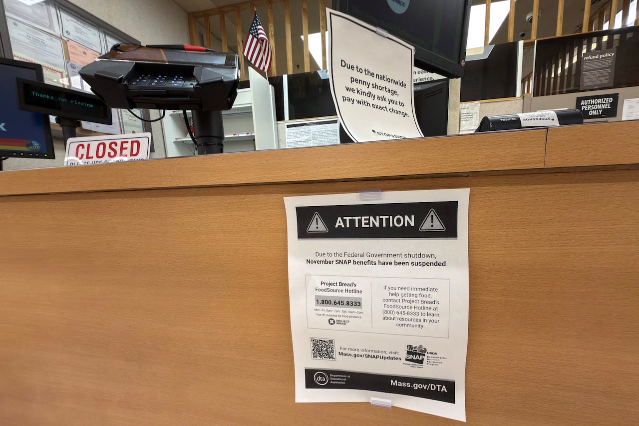 A series of signs are shown at a window and desk at a place of business, indicating that operations are closed.