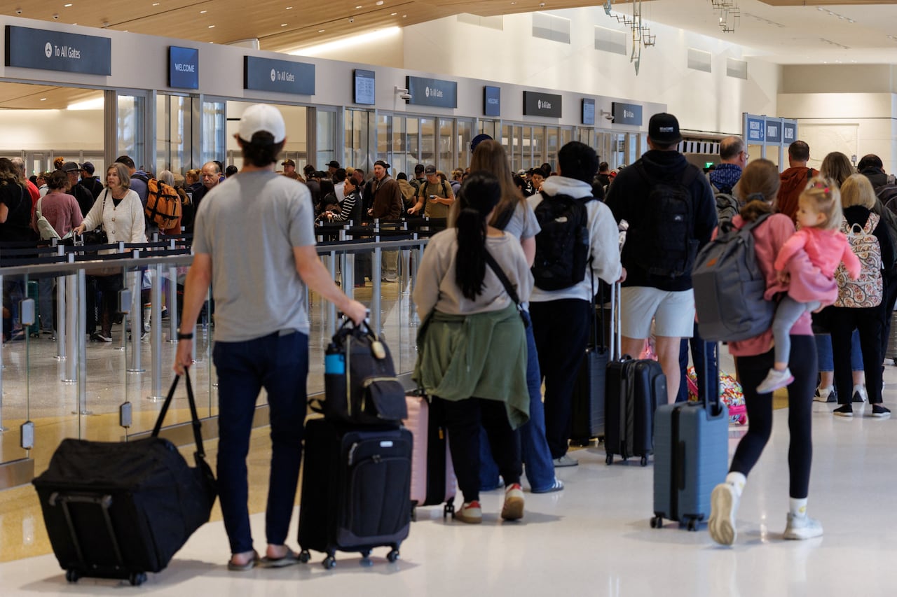 Travelers wait to clear security at a busy airport.