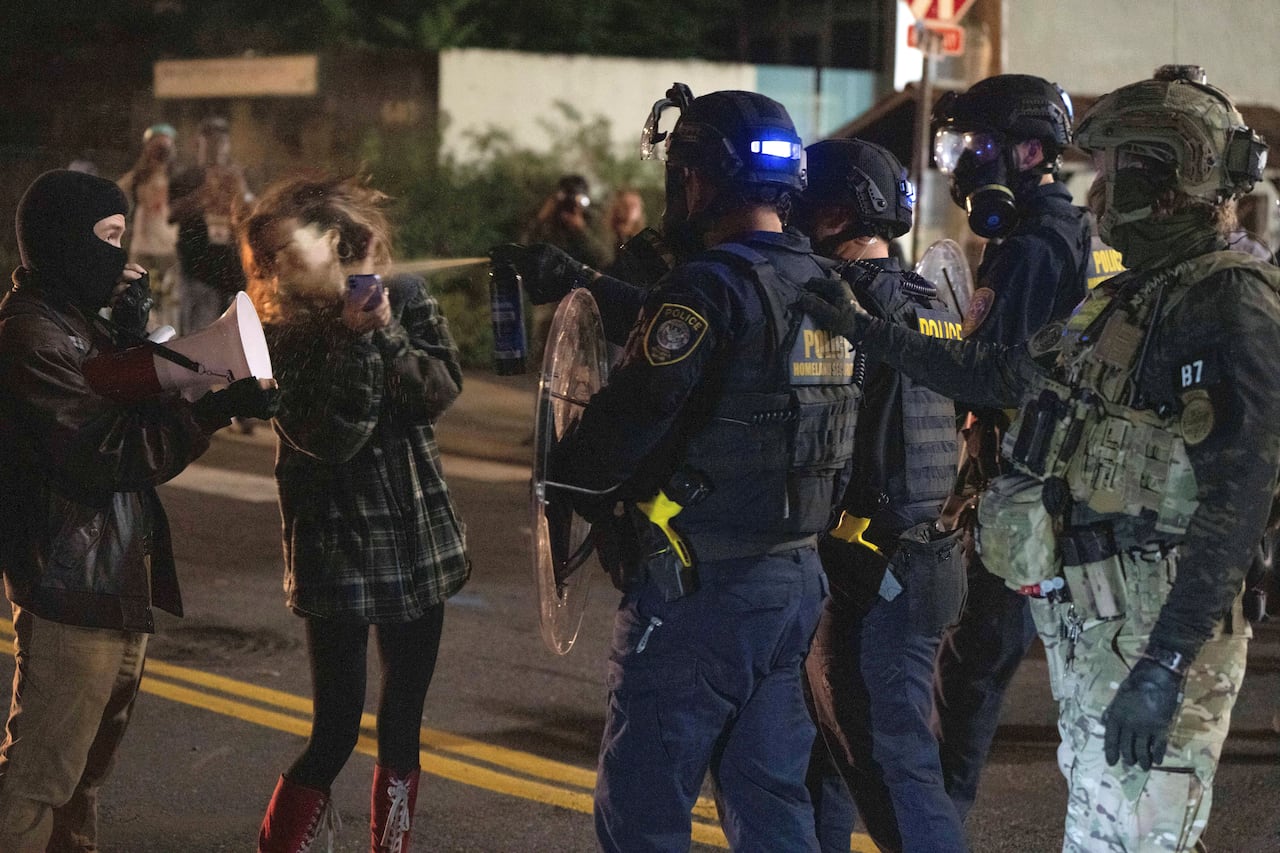 A police officer in riot gear pepper sprays a protester.