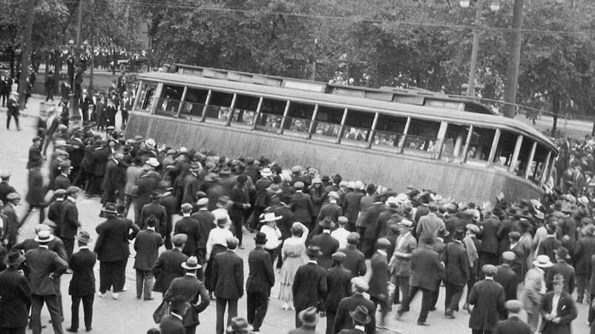 A large group of people tip over a streetcar