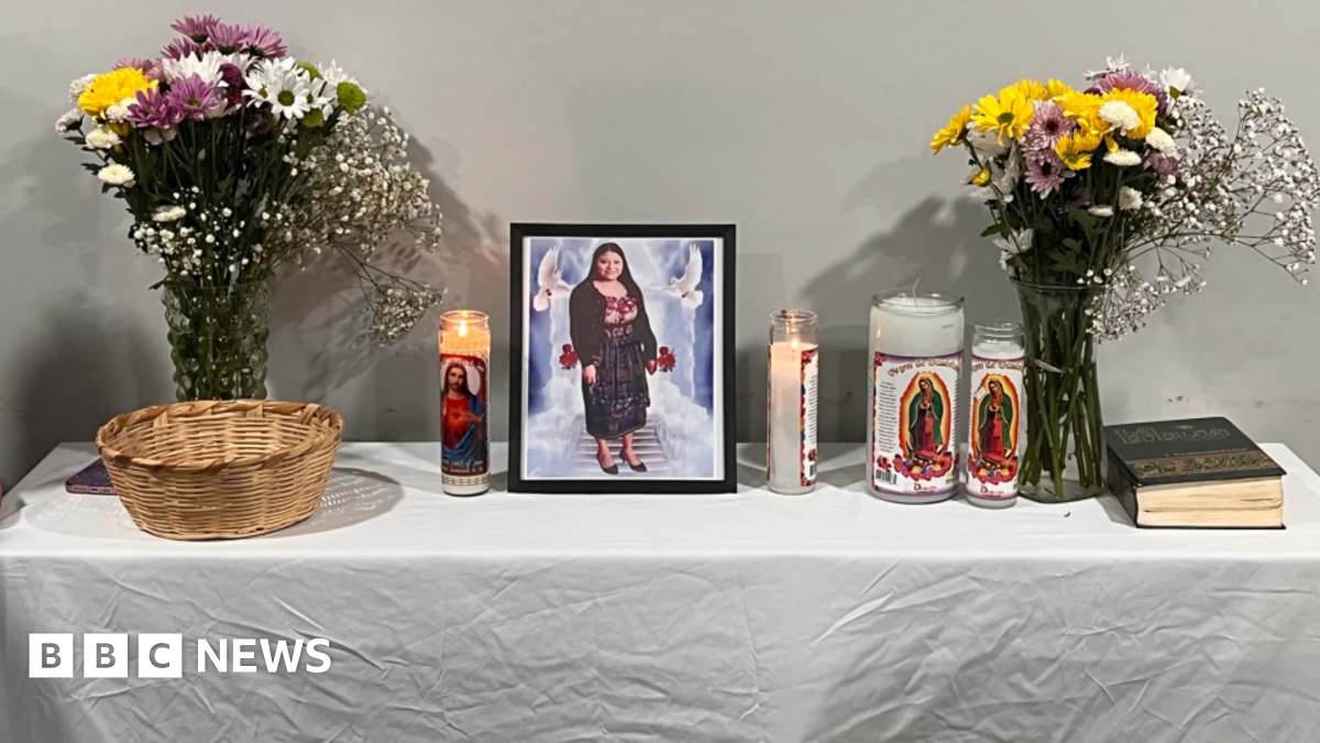 A photo of Maria Florinda Rios Perez is in a frame on a table with candles and flowers