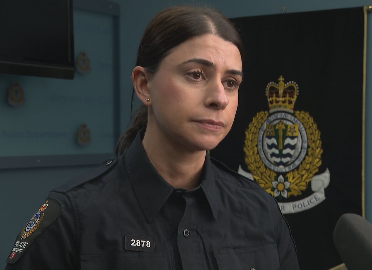 A police officer looks pensive next to a large logo.