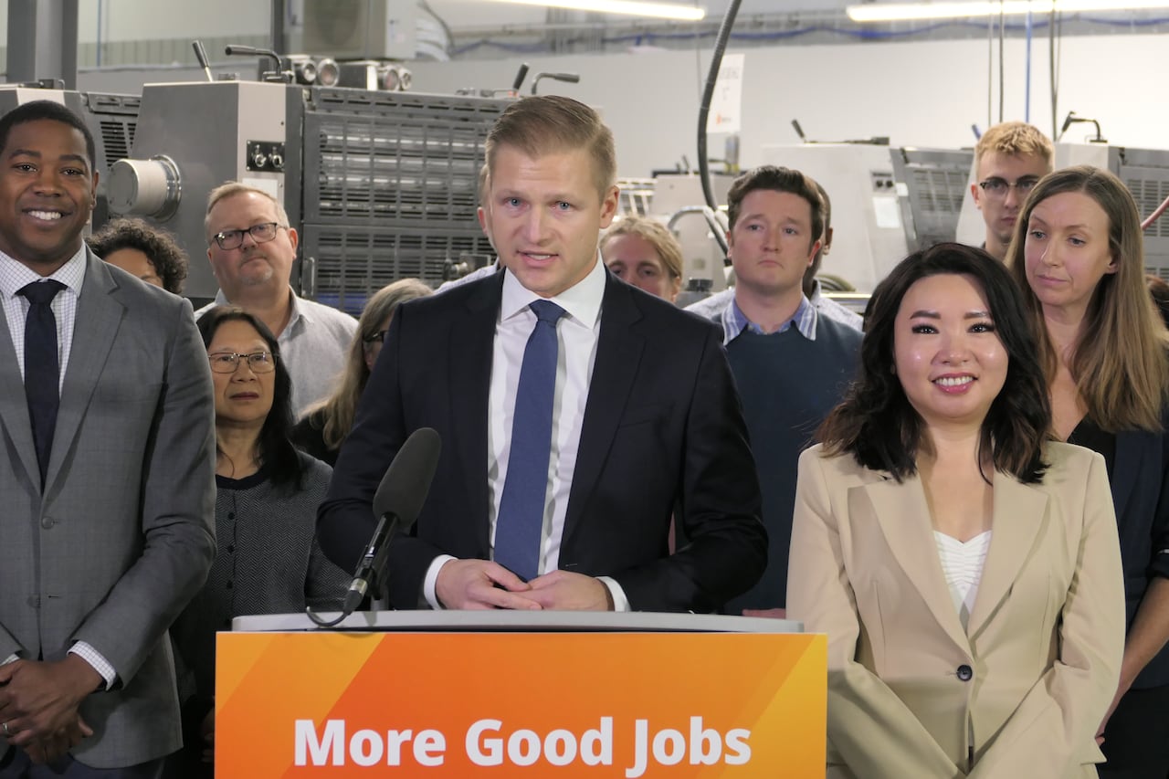 A man surrounding by people stands in front of a podium.