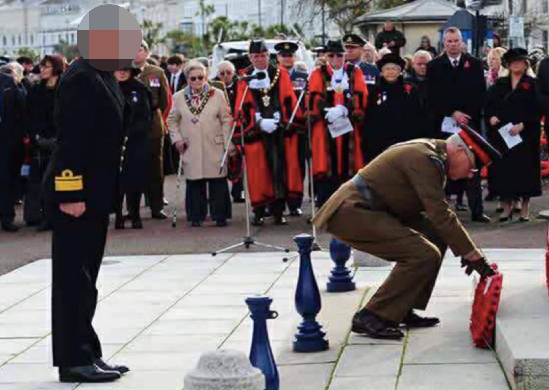 The man, alleged to be a fake rear admiral, watches another serviceman lay a poppy wreath at Llandudno's war memorial