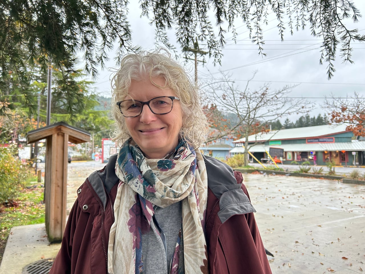 a woman stands in a park overlooking shops
