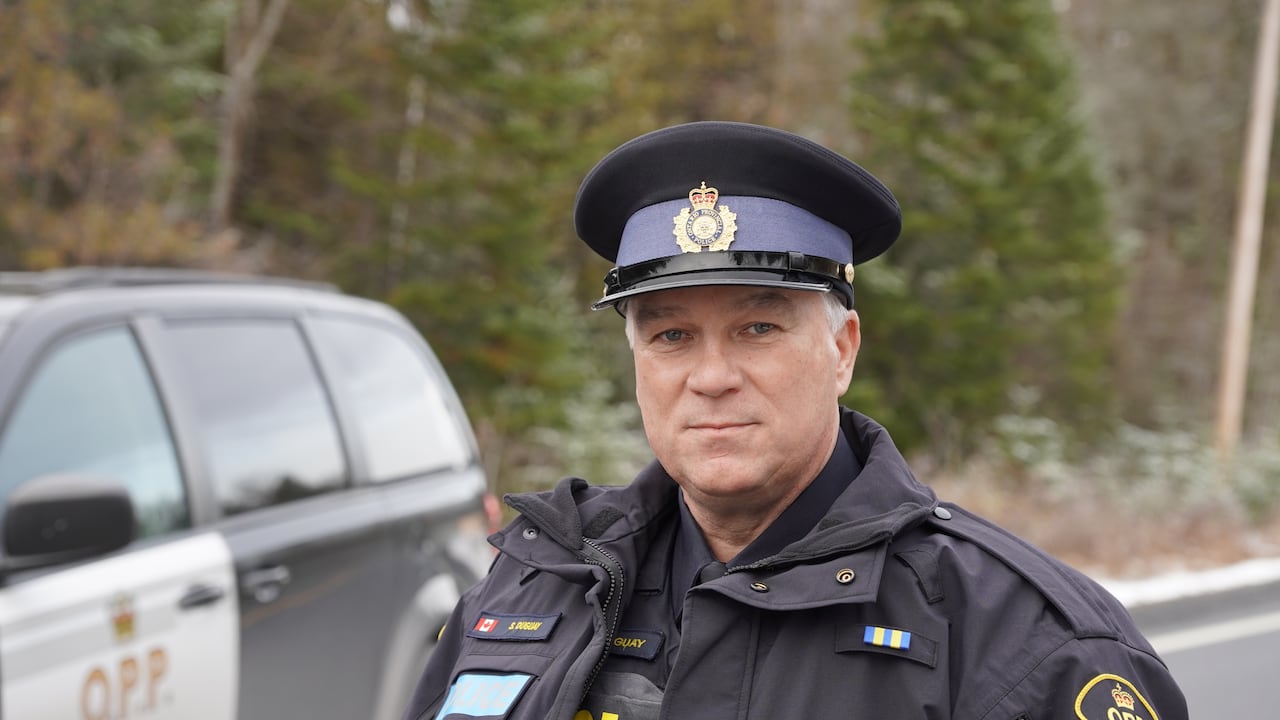 A white male police officer looks into the camera.