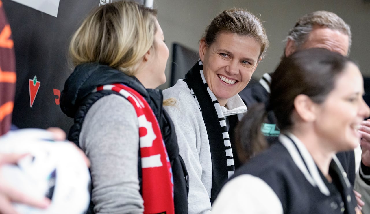 A women's soccer player smiles during a fundraising announcement.