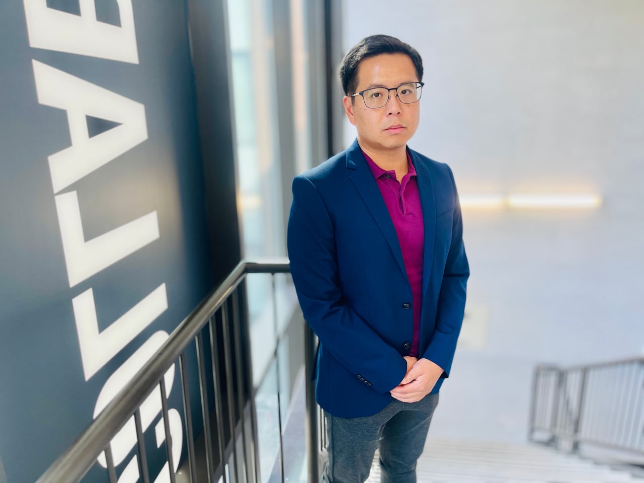 Man in suit standing on stairs, looking at the camera