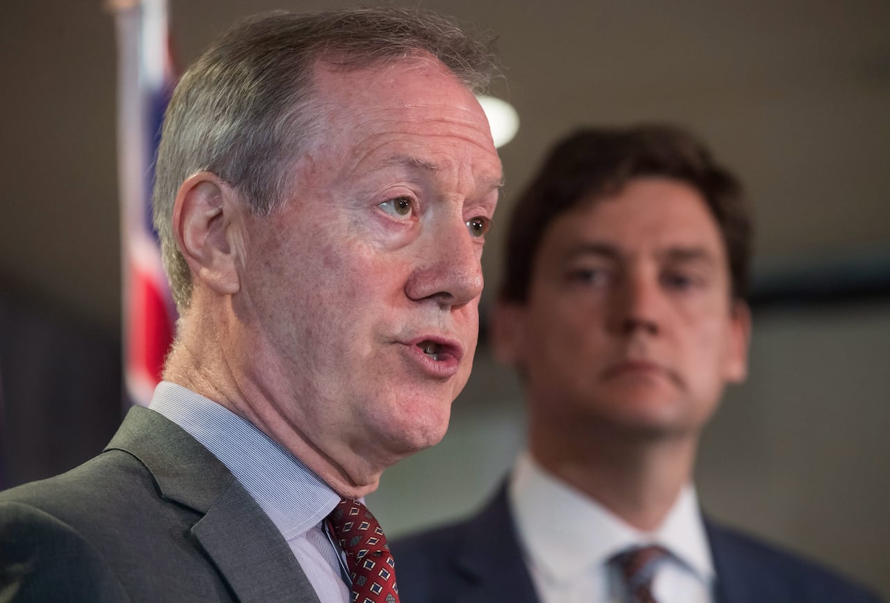 Peter German, front left, former deputy commissioner of the RCMP, stands in front of David Eby, premier of British Columbia
