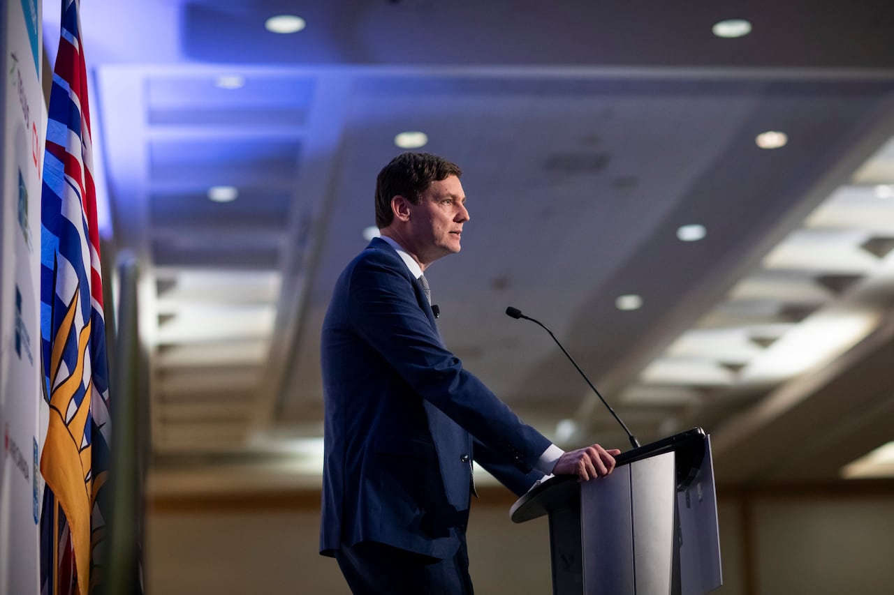 A tall man speaks at a podium, pictured in profile.