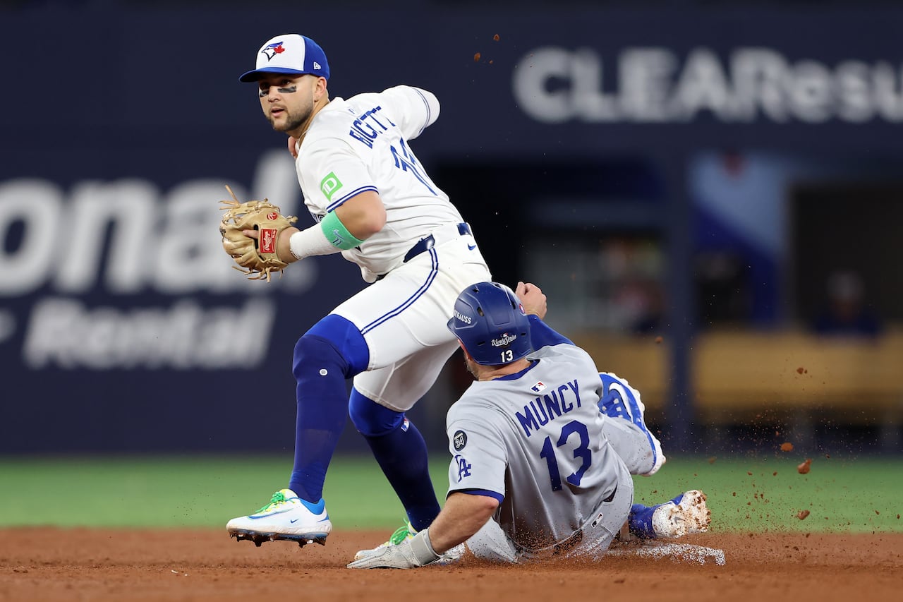 A baseball fielder prepares to throw, as an opposing player slides toward the bag at his feet
