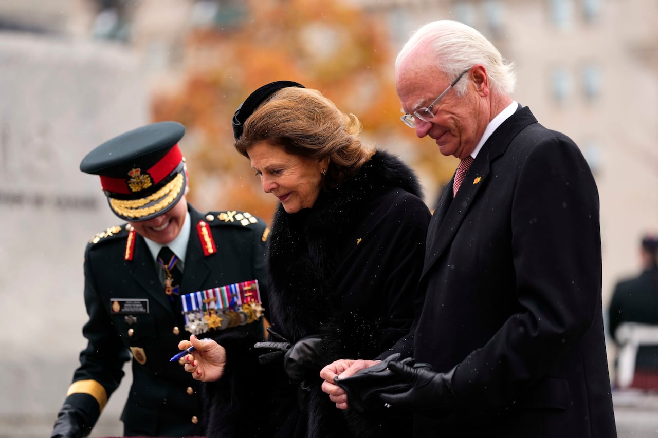 A man and two women - one in a military uniform - lay a wreath.